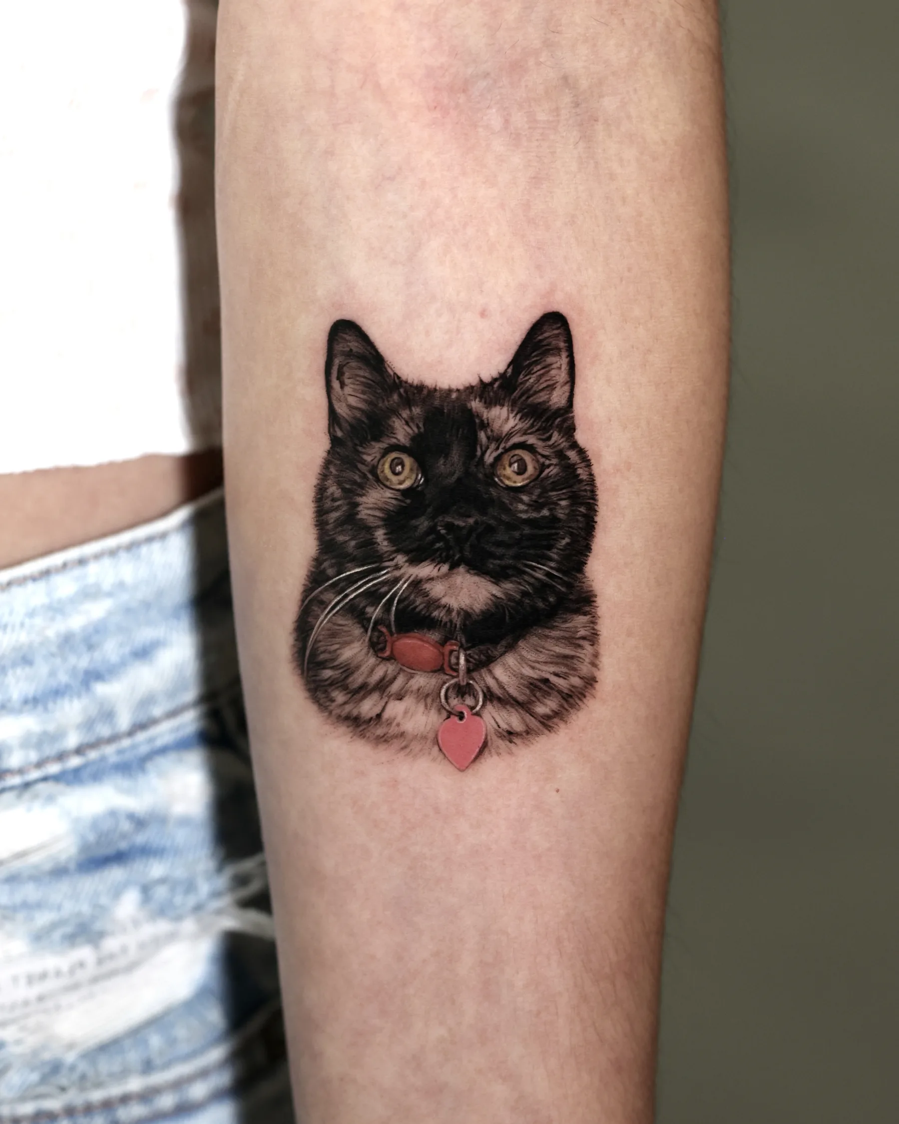 Black and grey tortoiseshell cat tattoo with a red collar and heart tag