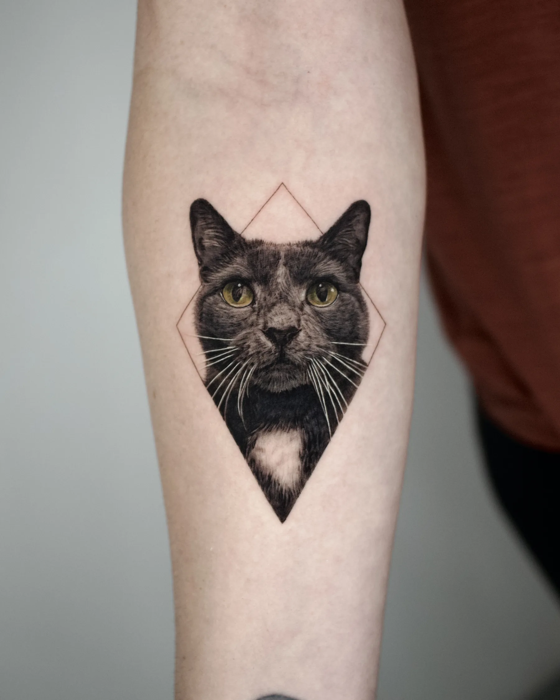 Black and grey cat portrait tattoo with green eyes in a diamond outline