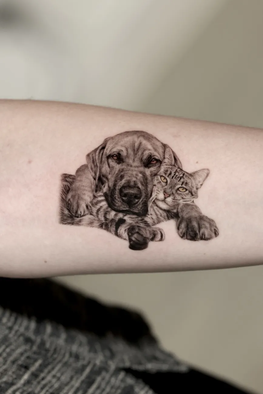 Black and grey realistic tattoo of a dog and cat resting together